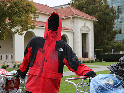 A statue of a homeless person holding onto two shopping carts outside Deihl Hall.