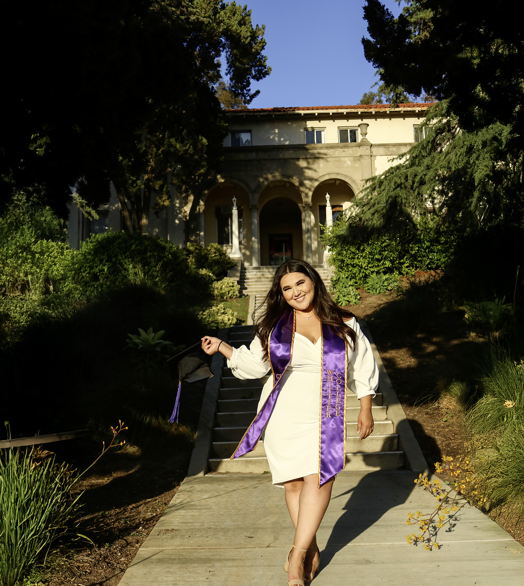 Destinee wearing graduation sash in front of building