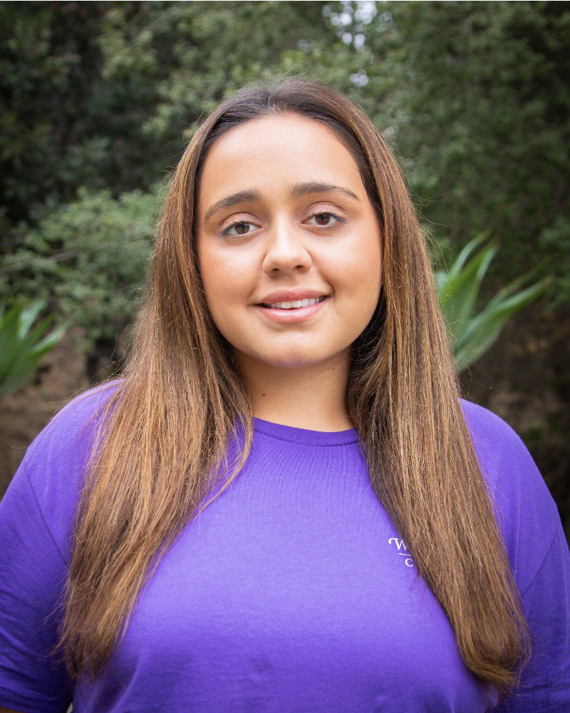Angelina Leon standing in front of plants wearing Whittier College shirt