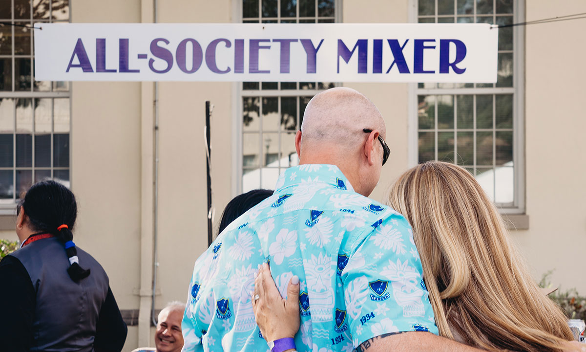 Two people in front of All-Society Mixer banner