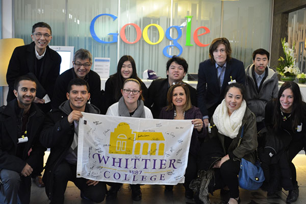 Students in a business administration class and professor Lana Nino hold a Whittier College flag in a grou photo at Google.