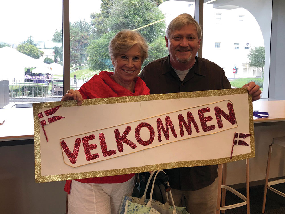Two alumni holding a sign that reads "velkommen"