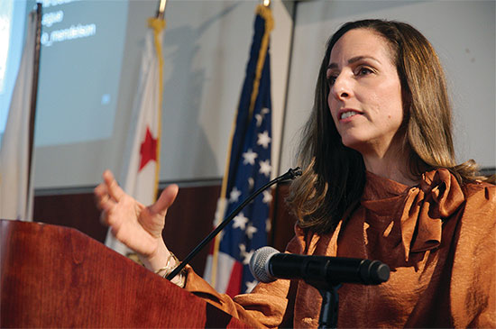 Joanna Mendelson delivers a presentation at a podium.