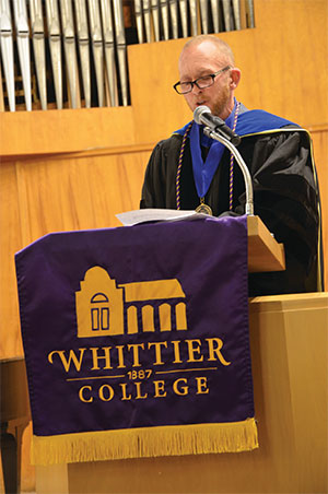 Wearing academic regalia, Professor Sal Johnston gives a speech at a podium in Memorial Chapel.