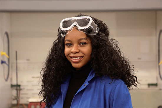 Olive Anagu in chemistry lab coat and goggles.