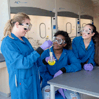 A professor and two students work in a chemistry lab.