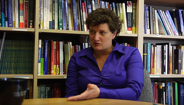 Professor Sara Angevine sits at a desk in her office.