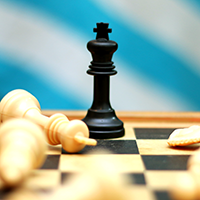 A black king chess piece stands on the board, with fallen white pieces surrounding it.