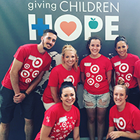 Economics major Susan Rosett and several other people stand in front of a "giving children hope" banner.