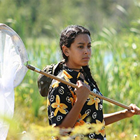 Stephanie Alcala holds a net in the field.