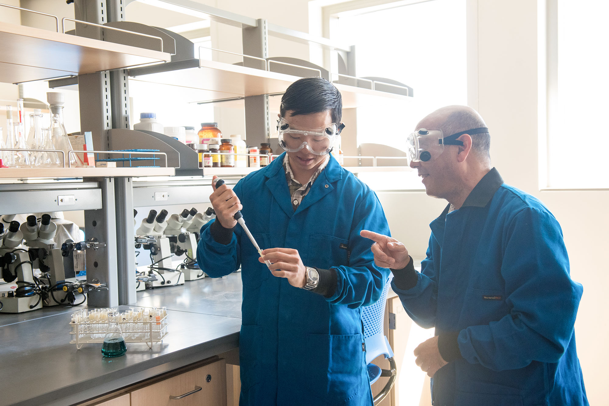 Student Ryan Nakamura and Professor Devin Iimoto perform an experiment in the chemistry lab