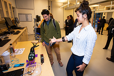 Danica Cooley demonstrates a myoelectric arm, an example of a robotic prosthetic, to a student.