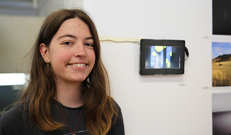 Lauren Swintek stands in front of her animated short, Celestial Bodies.