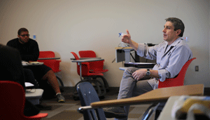 Richard Blanco sitting in a desk talking to students in a classroom