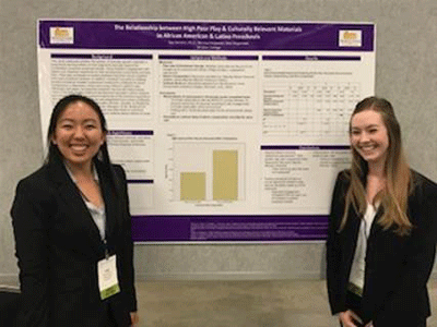 two students stand in front of their posters at a conference