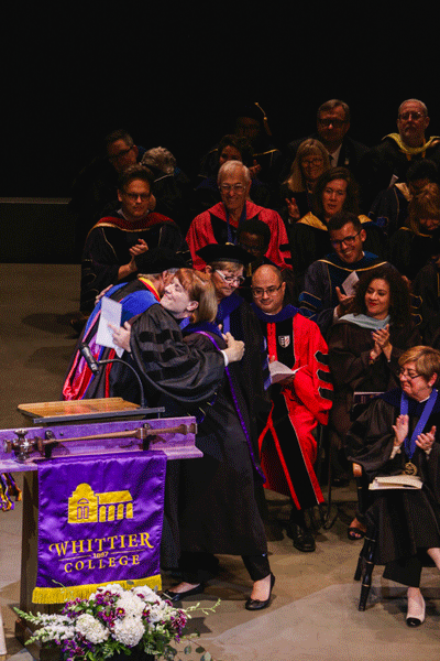 Speaker and presenter hugging on stage