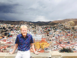 Max Hoverstein sits in front of colorful houses