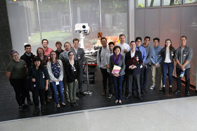 Students pose in front of a model of a space exploration robot.