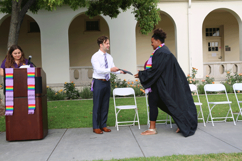 A student in a graduation gown receives her diploma