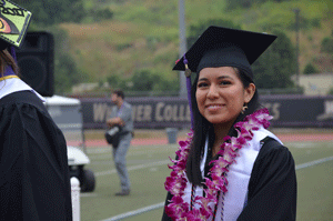 Graduate Mirka Pojoy in a cap and gown on the field