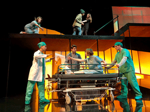 A group of students in medical costumes perform on stage