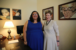 The student president for the day stands next to President Herzberger in her office