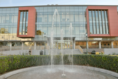 A photo of the front of the science and learning center with a water fountain in front