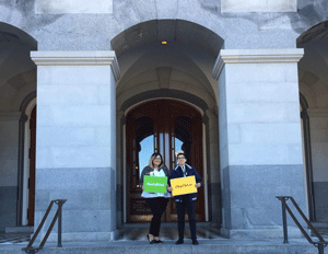 Students hold sigs while standing in front of the California State Capital 