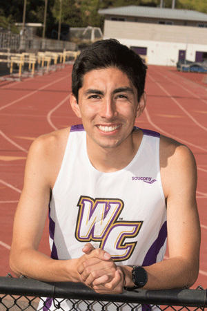 Ruben Solorza stands on the track in his track & field uniform