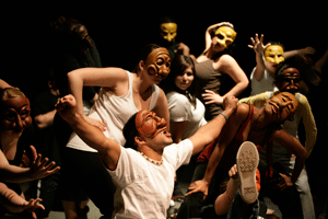Students perform on stage wearing masks