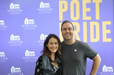 Two alumni in front of a photo backdrop