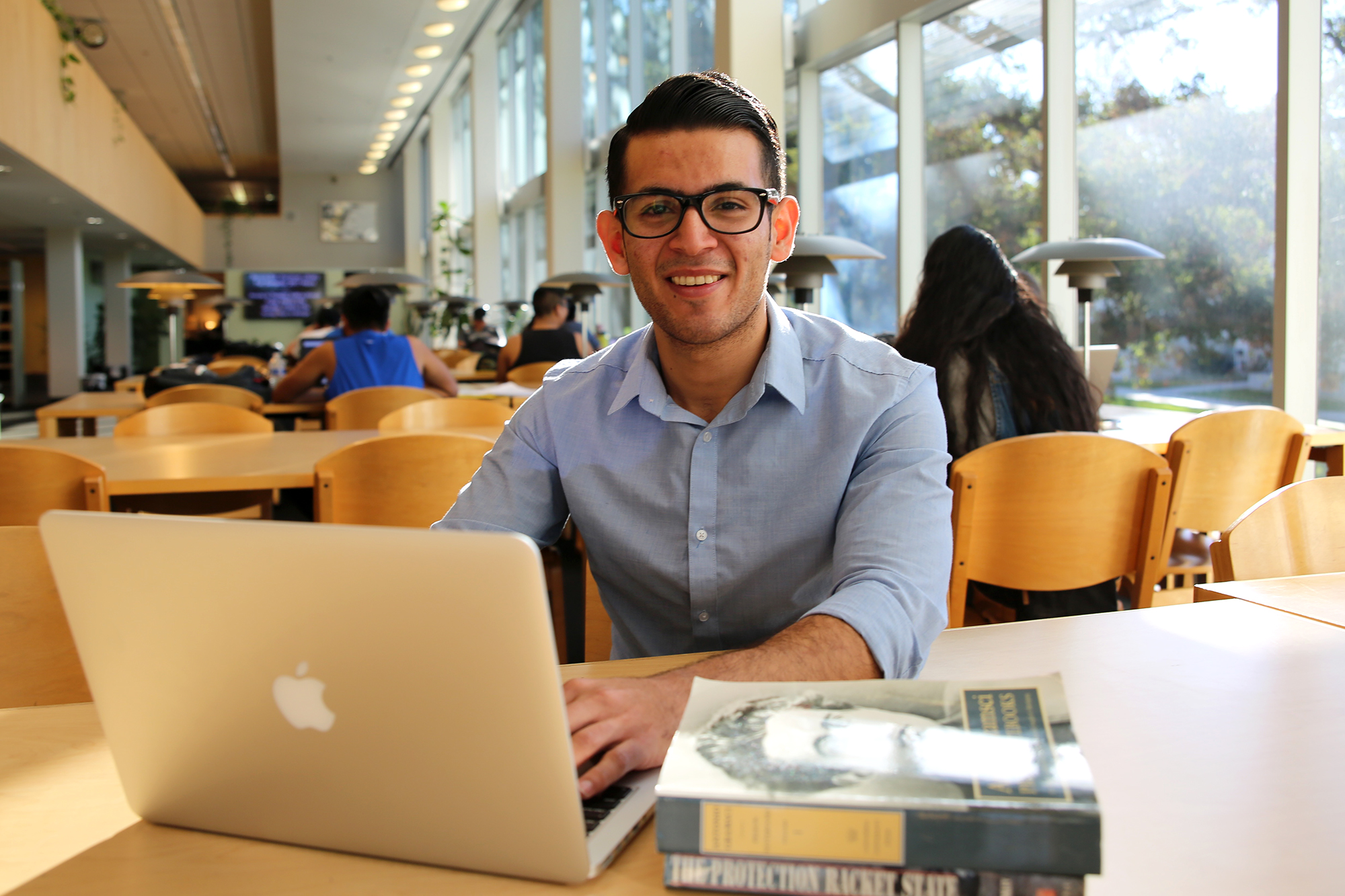 Political science major Roberto Bonilla sits in front of his laptop and two books in the Wardman Library.
