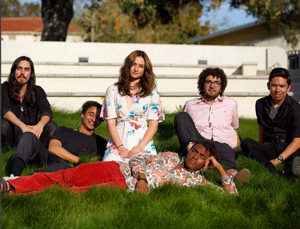 Six members of the band, 7 Planets like Earth, sit in the lawn on campus