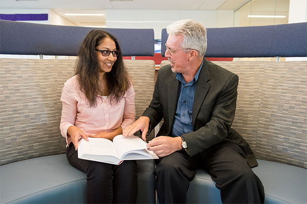 Physics professor Lagan and a student in a discussion, with a textbook.