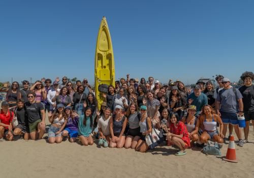 Group of Whittier College students on beach in front of Kayak