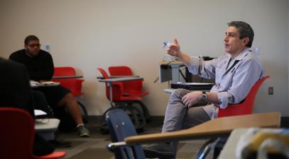 Richard Blanco sitting in a desk talking to students in a classroom