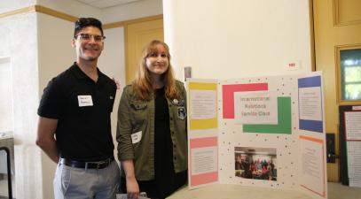 Participants pose beside their poster board presentation
