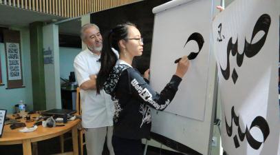 student creating calligraphy art on easel 