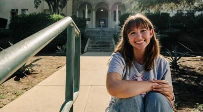 Student sitting on Whittier College's campus and smiling 