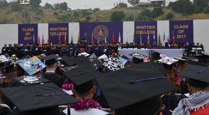 graduates in caps and gowns face the stage at commencement