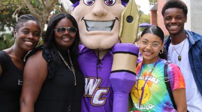 A family of four stand with Johnny Poet, the school mascot