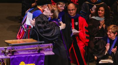 Professor and presenter hugging on stage