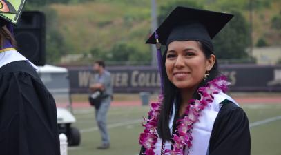 Graduate Mirka Pojoy in a cap and gown on the field