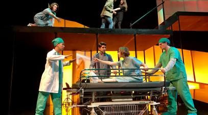 A group of students in medical costumes perform on stage