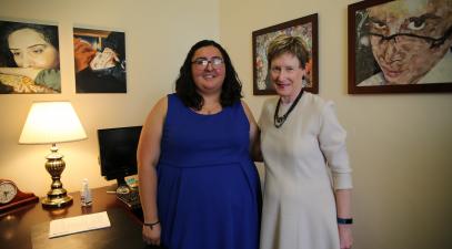 The student president for the day stands next to President Herzberger in her office