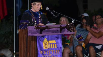 President of the College, Sharon Herzberger, in academic regalia stands at podium addressing audience