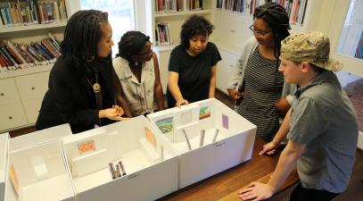 Imani Williford, India Ferguson, Rosalba Ponce, Caitlyn Keeve, and Jake Martin use a model of the Kluge-Ruhe galleries to plan their exhibition Songs of a Secret Country during the 2017 Summer Curatorial Research Project at the University of Virginia.