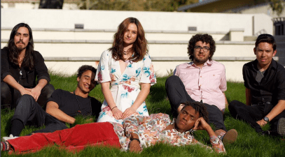 Six members of the band, 7 Planets on Earth, sit on the lawn on campus