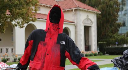 A statue of a homeless person holding onto two shopping carts outside Deihl Hall.