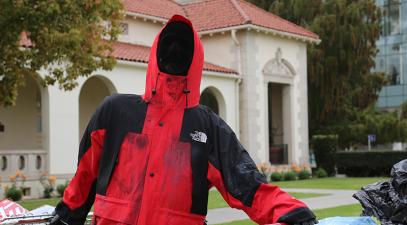 A statue of a homeless person holding onto two shopping carts outside Deihl Hall.
